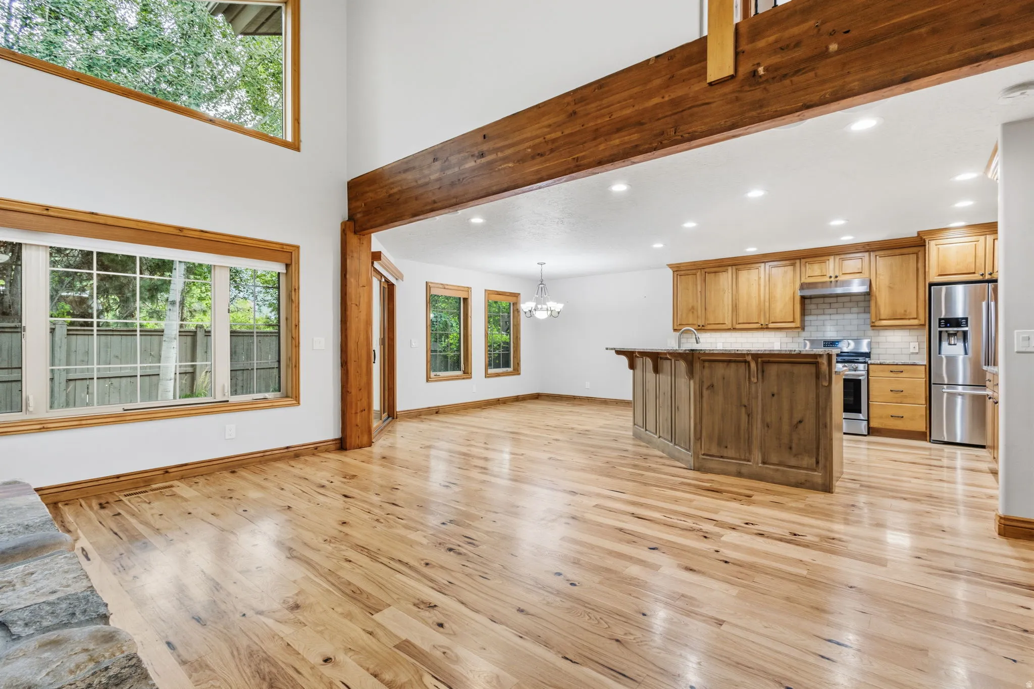 Open-concept living space featuring high ceilings, wood-finish flooring, and exposed timber beams
