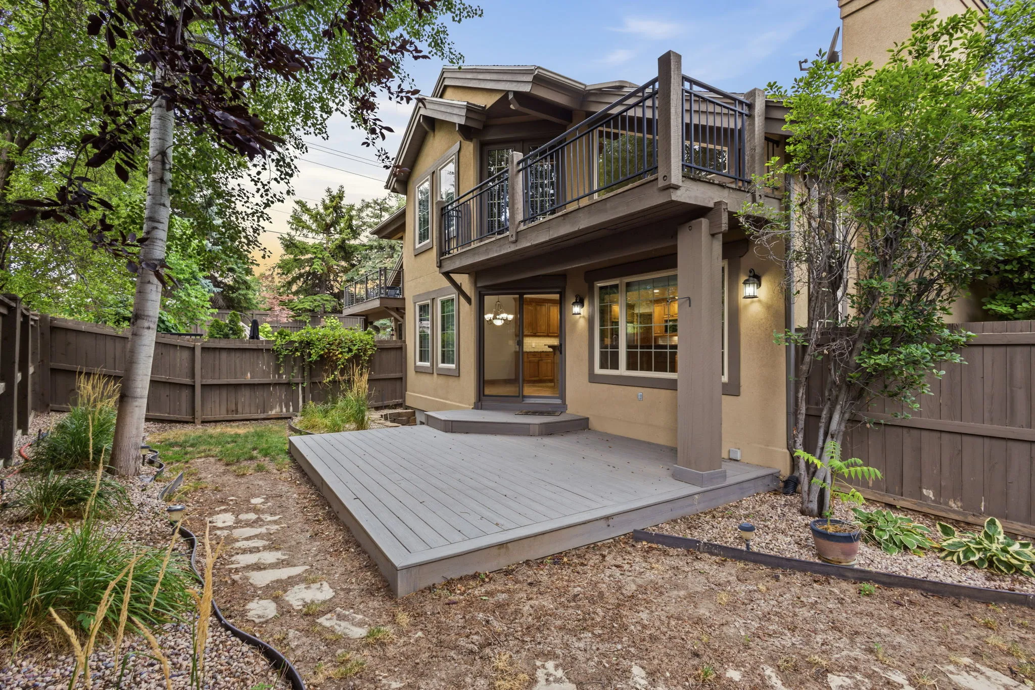Multi-level rear exterior featuring a composite deck, an upper-level balcony with metal railing, and a private fenced yard