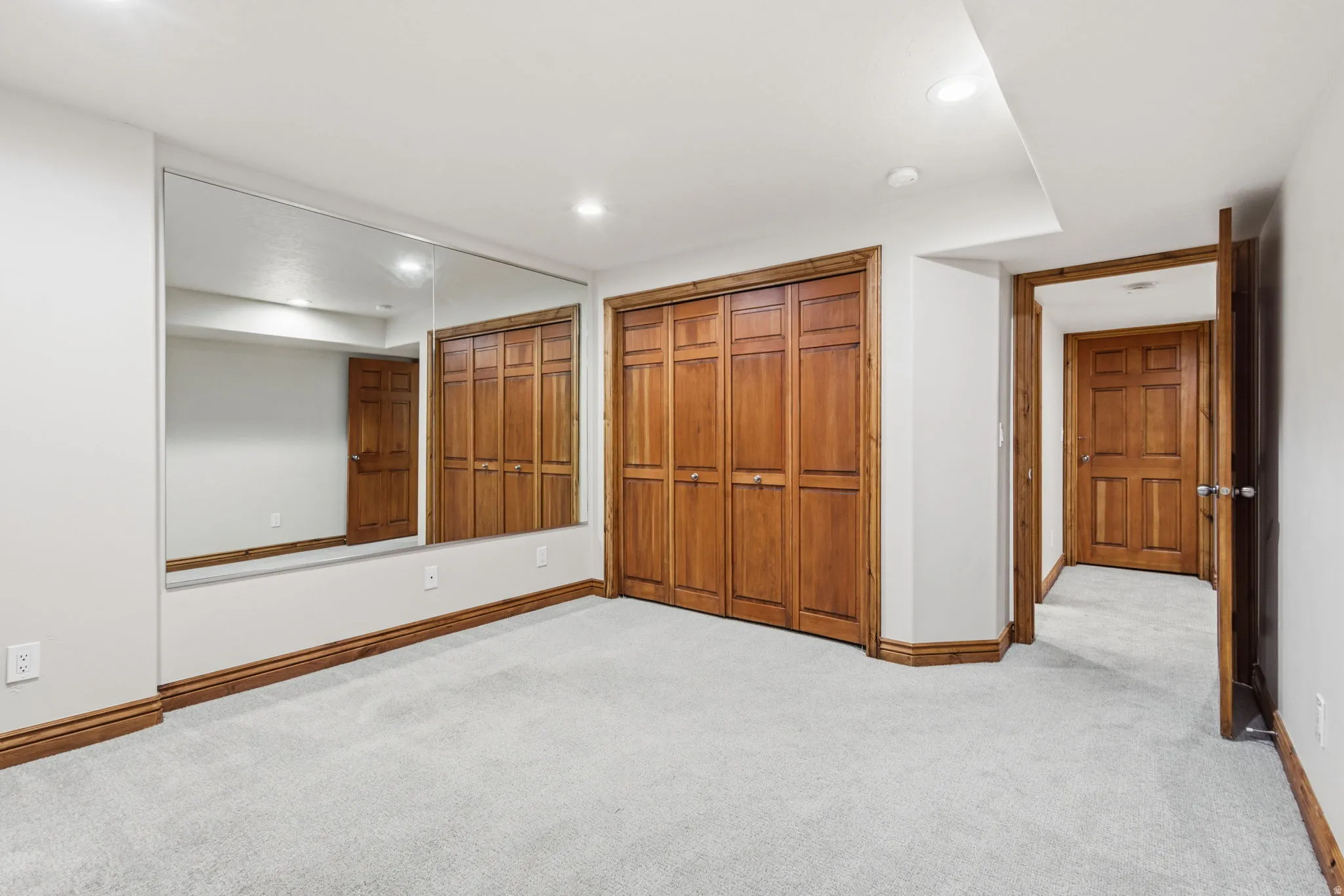 Wall-to-wall mirrored accent wall with a light gray carpeted floor