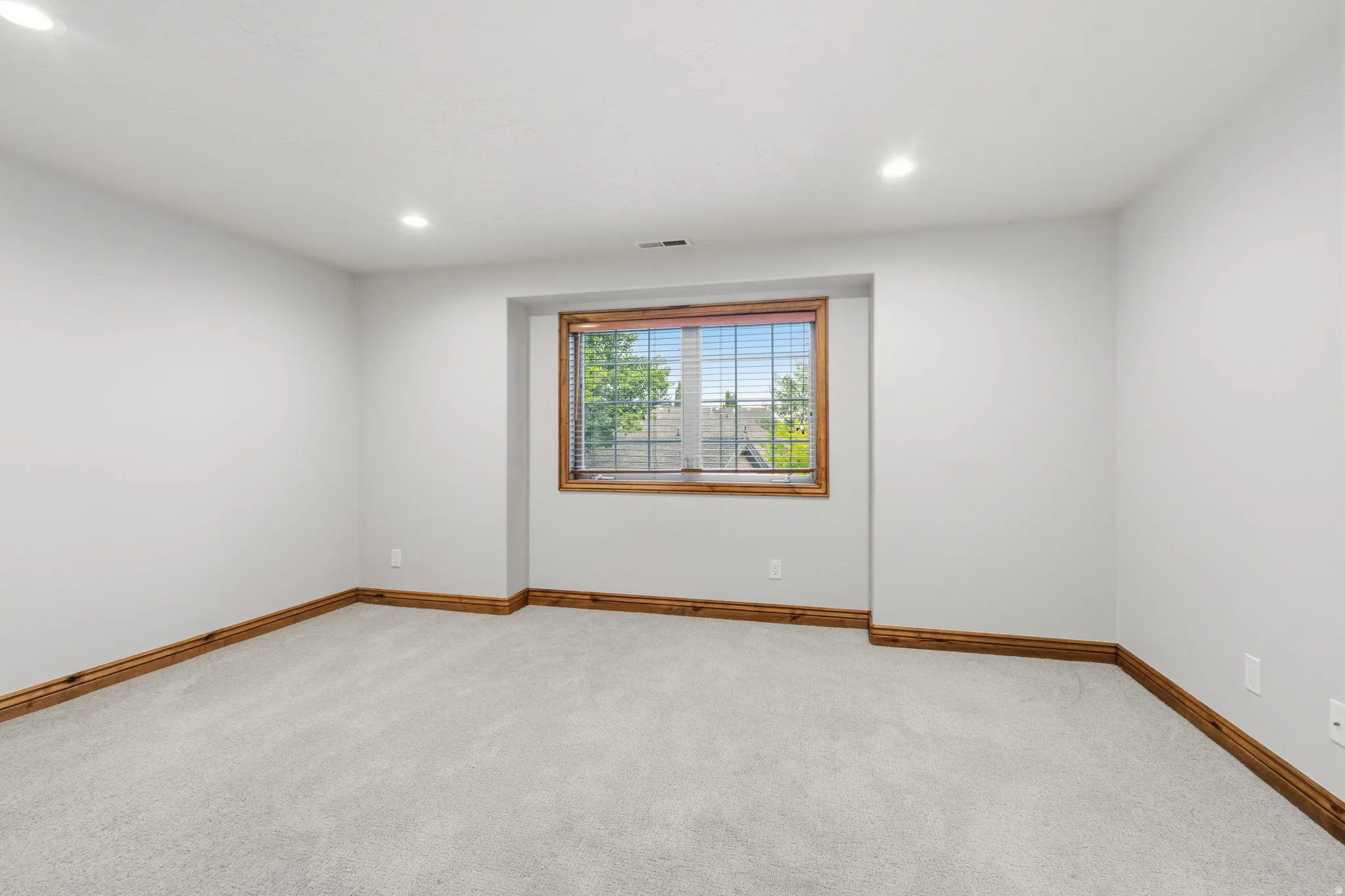 Spacious room featuring light gray carpeting, neutral wall finishes, and recessed lighting