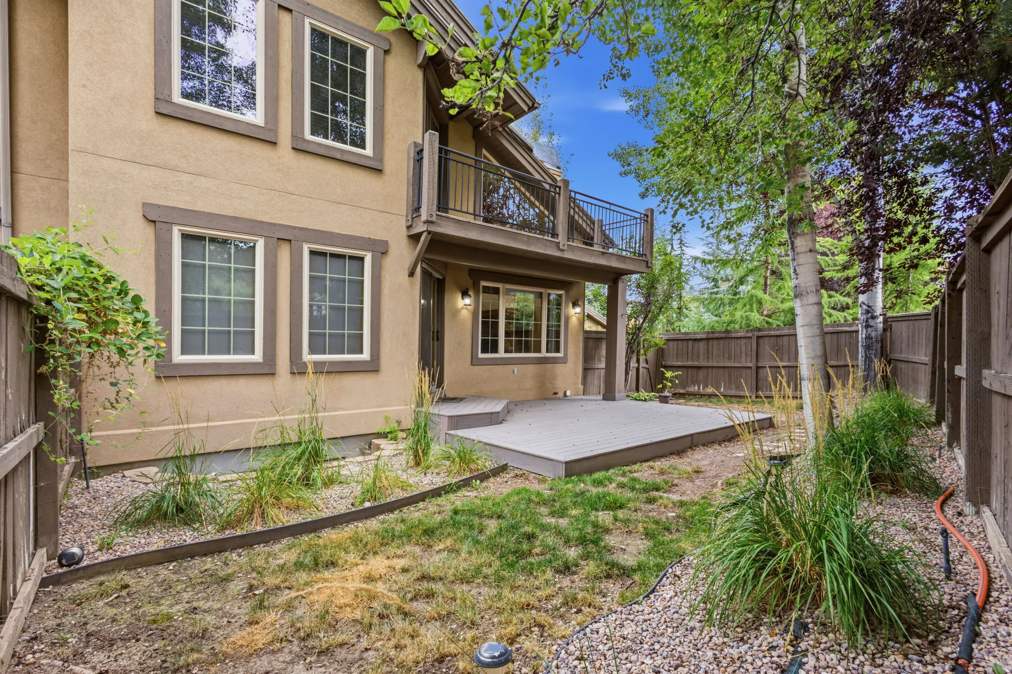 Rear exterior featuring a composite deck and an upper-level balcony with metal railing