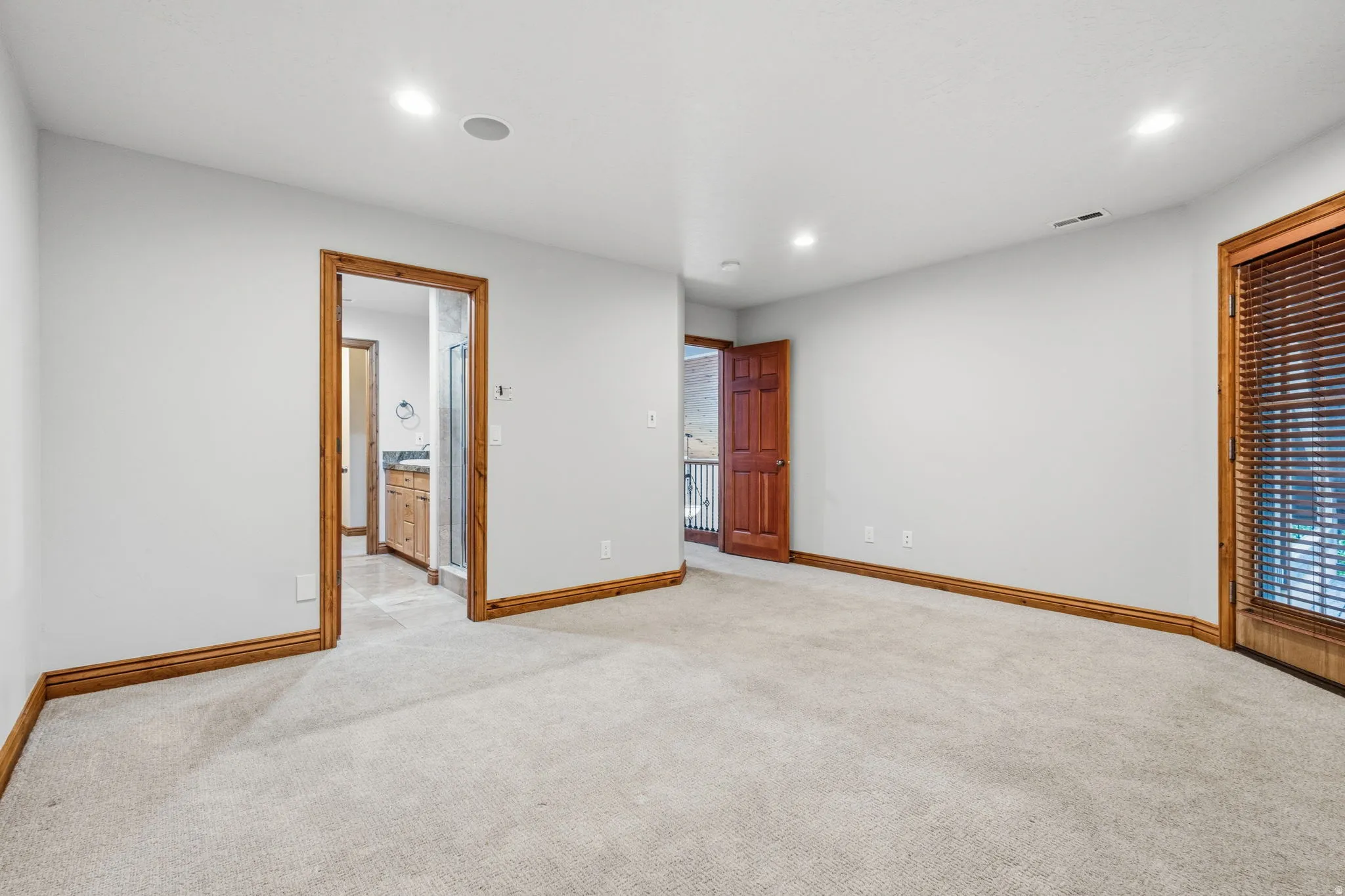 Carpeted room with recessed lighting and natural wood trim throughout