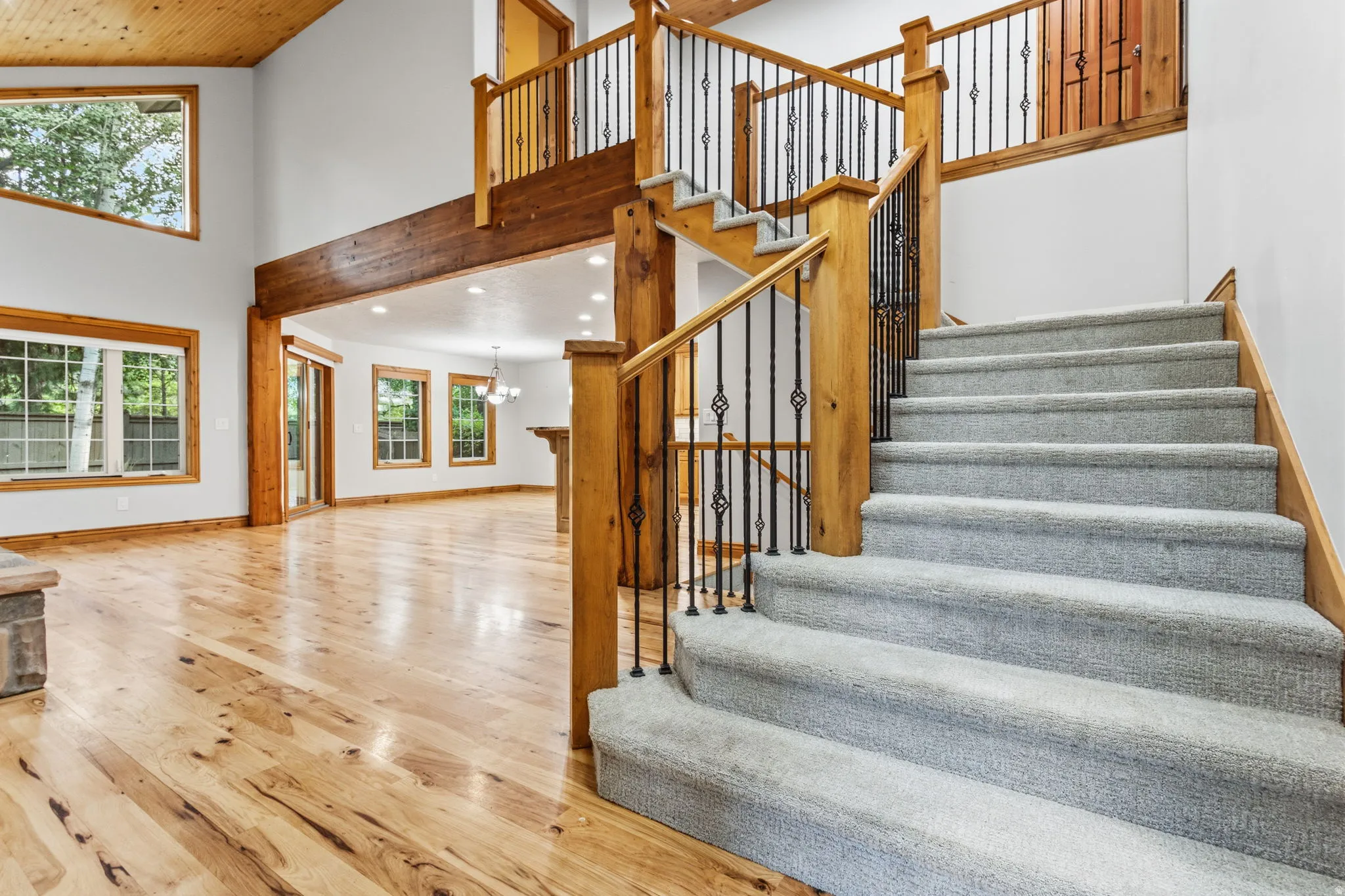 Grand foyer featuring a carpeted staircase with ornate iron balusters and a wood-finish handrail