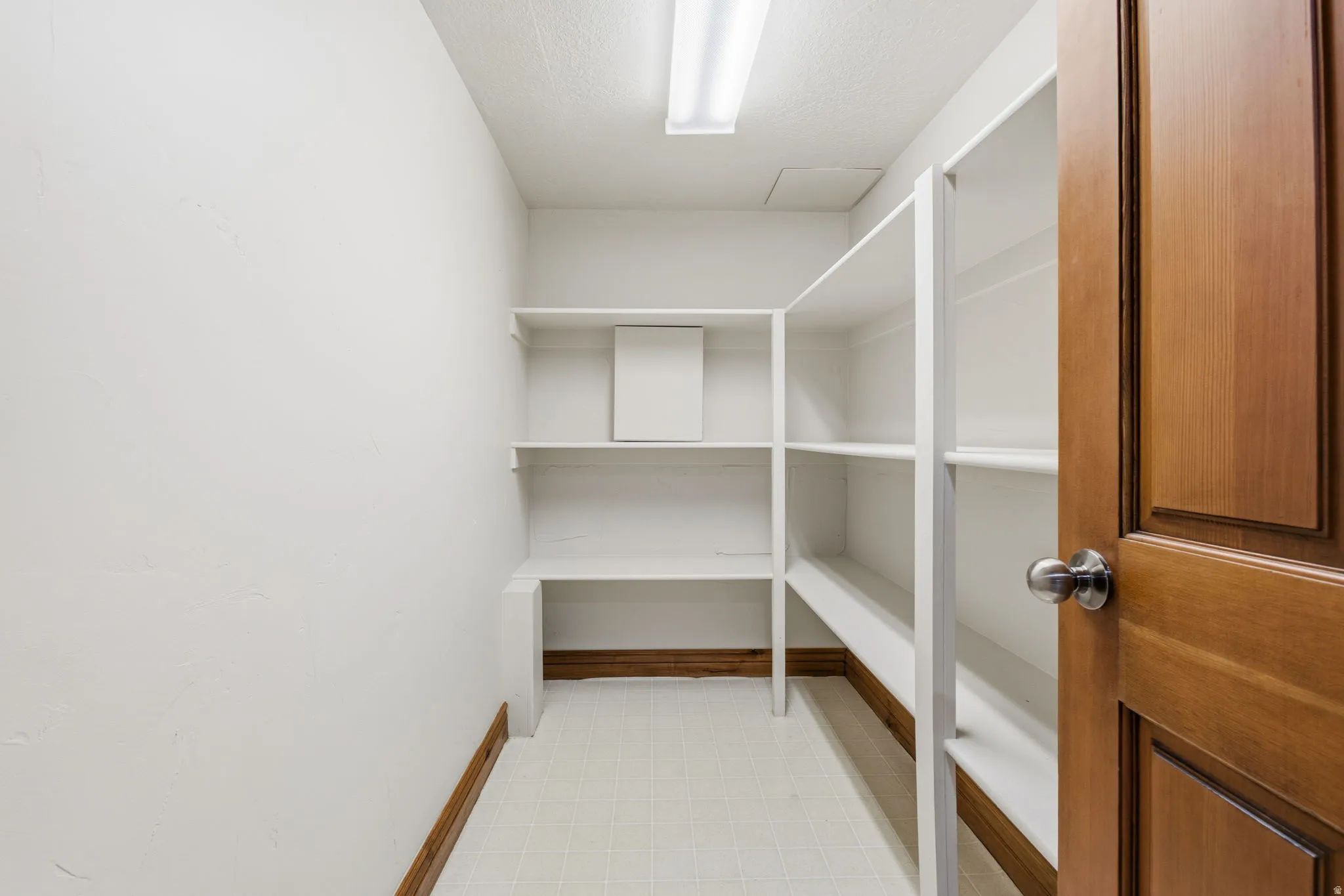 Pantry featuring extensive white shelving, white walls, and wood trim