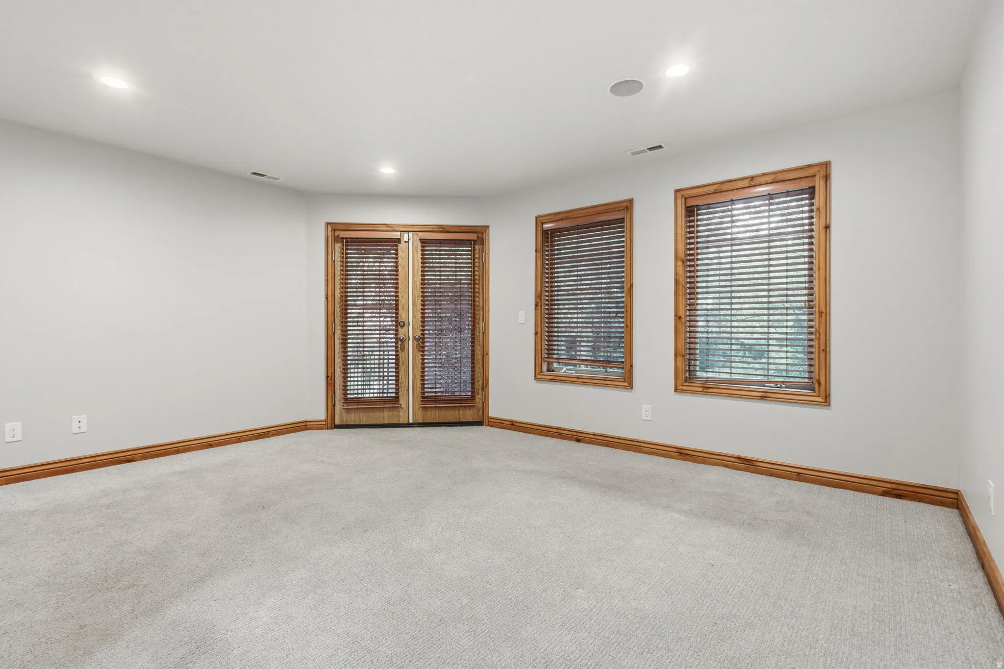 Recessed lighting illuminates this room featuring carpeted flooring and light gray walls