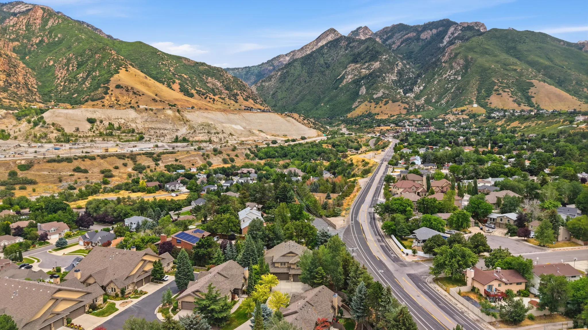 Expansive aerial perspective showcasing a residential area nestled at the base of prominent mountains