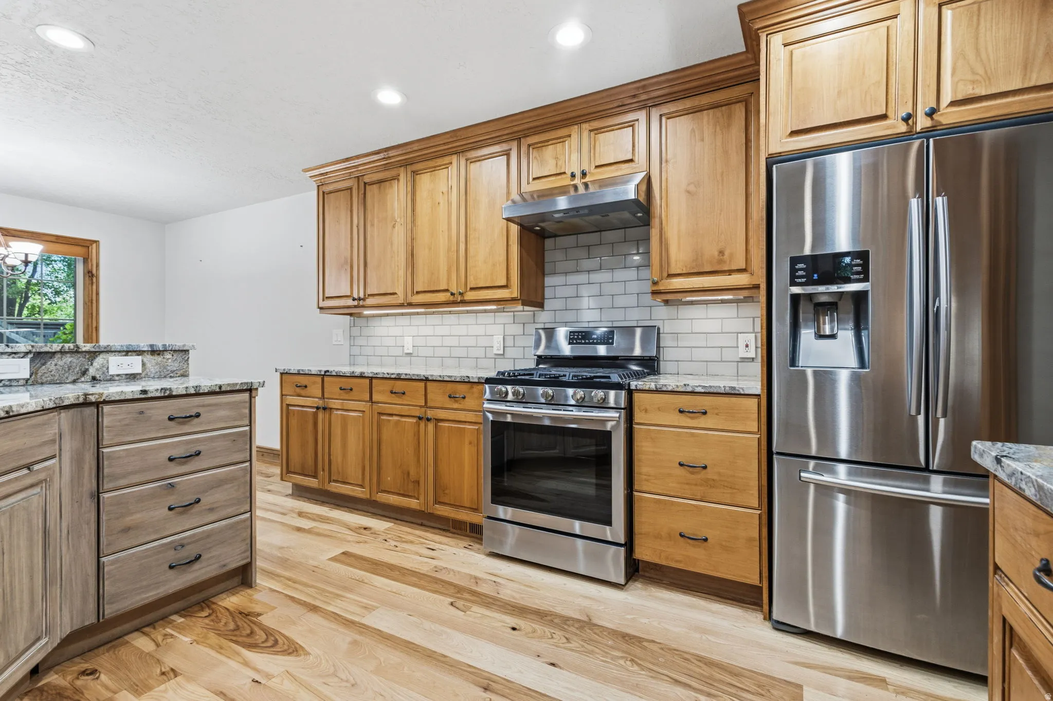 Kitchen with stainless steel appliances, wood-finish flooring, and light wood cabinetry