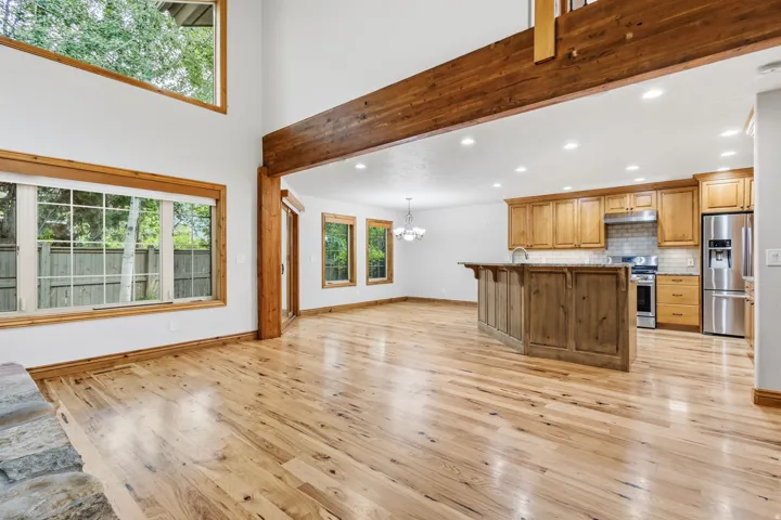 Open-concept living space featuring high ceilings, wood-finish flooring, and exposed timber beams