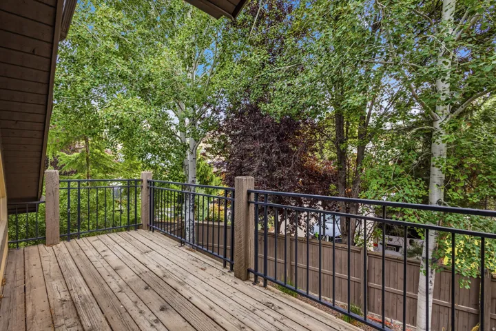 Wood-finish deck with black metal railings, surrounded by mature trees