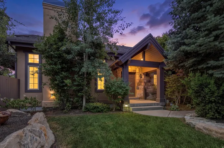 Gabled entry porch with stone accents, featuring a dark wood door and exterior lighting