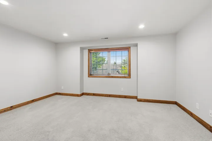Spacious room featuring light gray carpeting, neutral wall finishes, and recessed lighting
