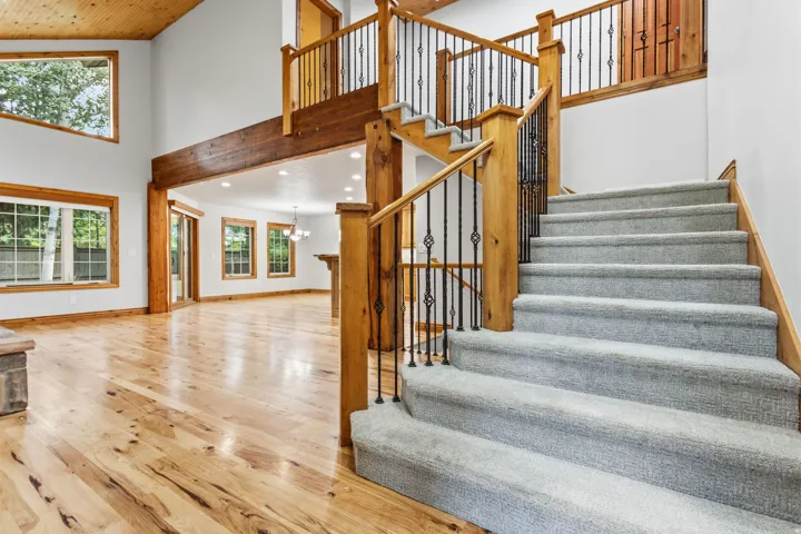 Grand foyer featuring a carpeted staircase with ornate iron balusters and a wood-finish handrail