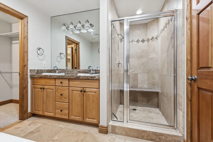 Bathroom featuring a glass-enclosed shower with tile surround and integrated bench