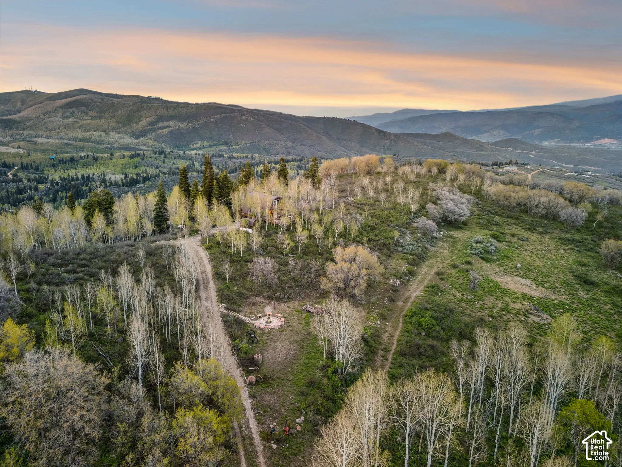 Aerial Overview - Overhead view showing the cabin, fire pit area, and drive approach on the wooded parcel.