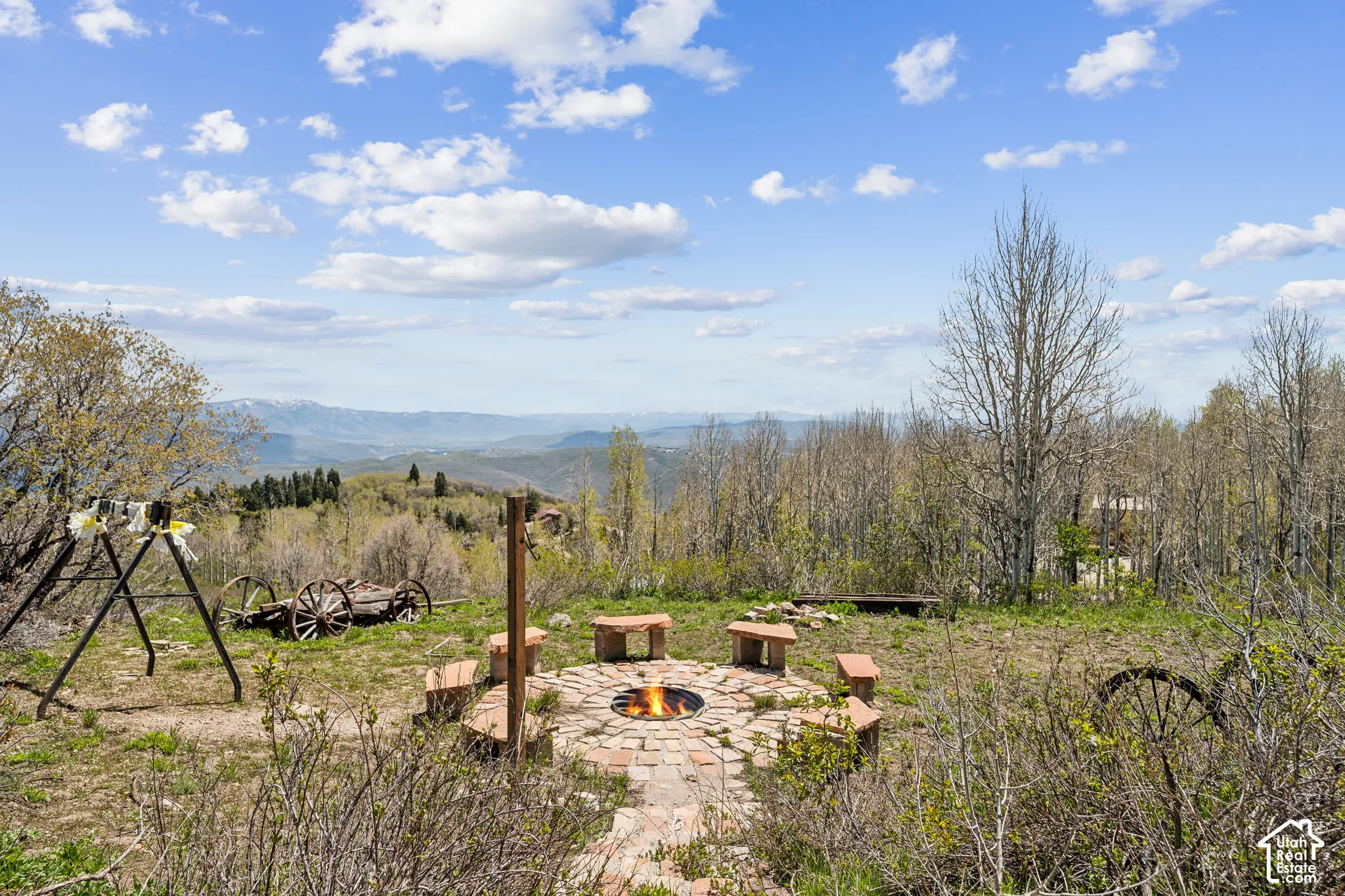 Fire Pit & Play Area - Gathering area with fire pit, bench seating, swing set, and vintage wagon-wheel accents.