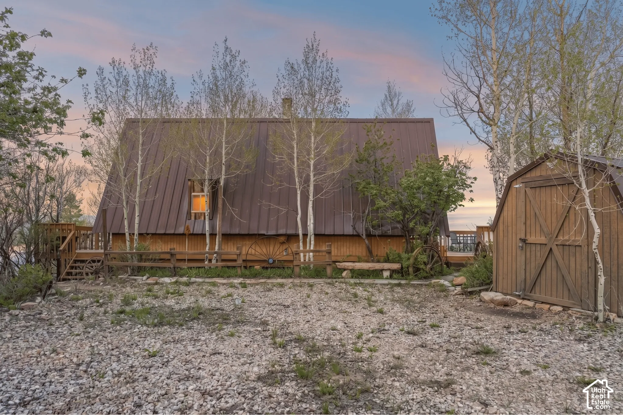 Exterior - Gravel parking area behind the cabin with a detached storage shed and level ground for vehicles or equipment.