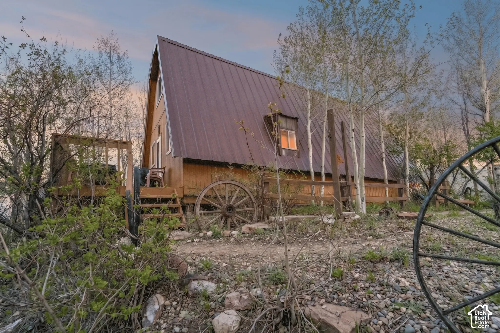 Exterior - Rear elevation showing the full length of the A-frame roofline, deck framing, and surrounding aspen stand.