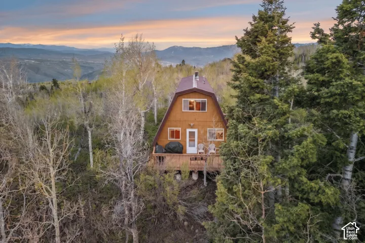 Aerial at Sunset - The cabin among aspens and pines at sunset, with the valley and mountain range in the distance.