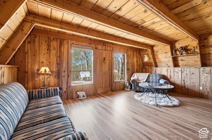 Main Living Area - Open living area with a door and windows to the front deck, sloped wood ceilings, and built-in shelving along the upper wall.