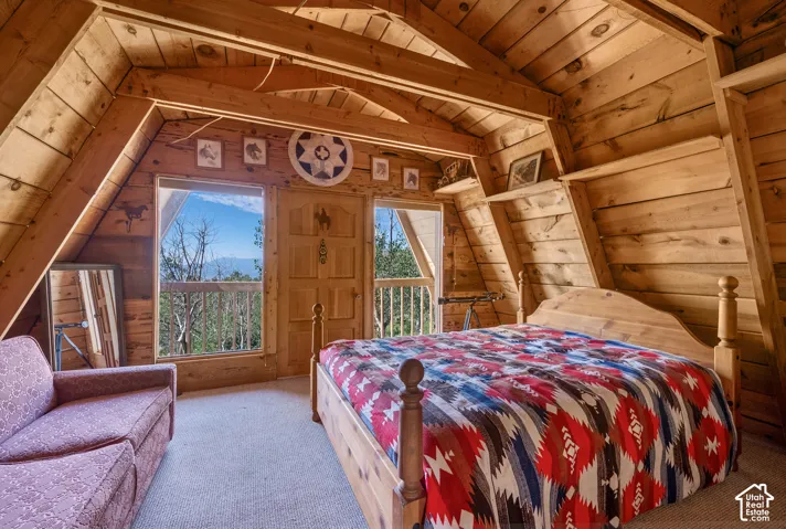 Primary Bedroom - Upper-level bedroom with vaulted A-frame ceilings, carpet, and a private door opening to the upper balcony.