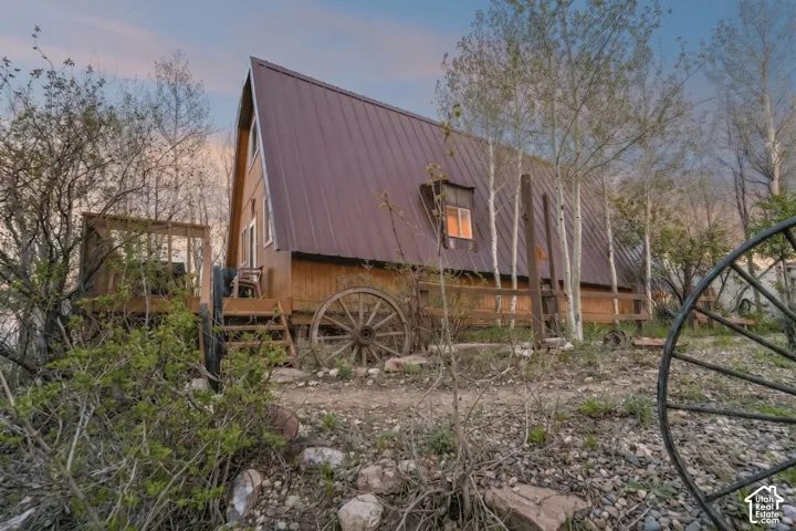 Exterior - Rear elevation showing the full length of the A-frame roofline, deck framing, and surrounding aspen stand.
