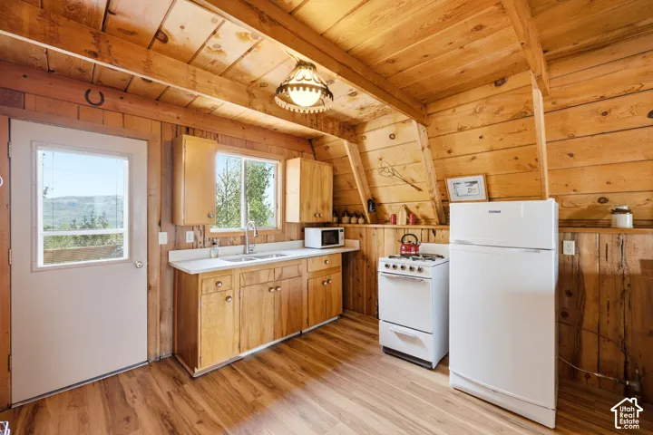Kitchen - Full-size range and refrigerator, stainless sink, and generous counter space, with windows above the sink framing the tree line.