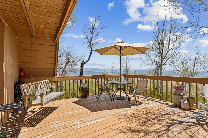 Deck & Mountain Views - Open-air dining space with an umbrella table and swing, positioned to take in the valley and mountain range beyond.