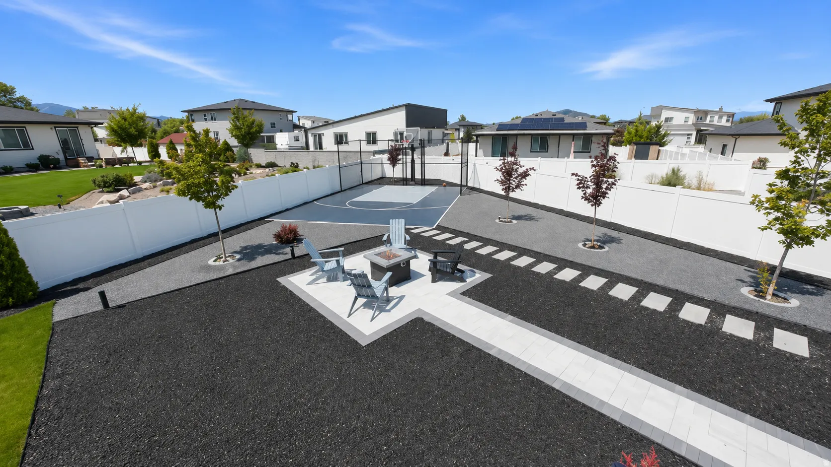 Expansive outdoor area featuring a full-size sports court, a paved patio with a built-in fire pit, and a pathway with stepping stones