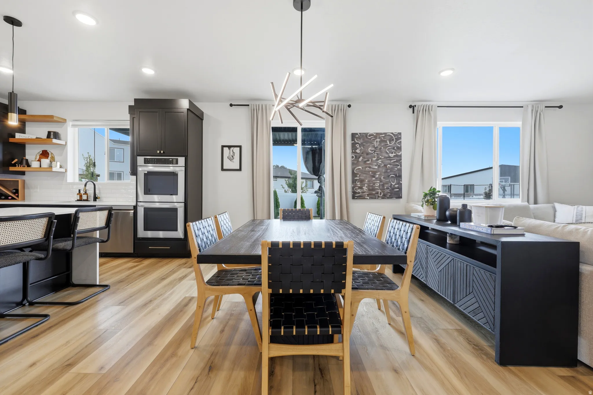 Open-concept living space featuring wood-finish flooring, a modern linear chandelier, and recessed lighting
