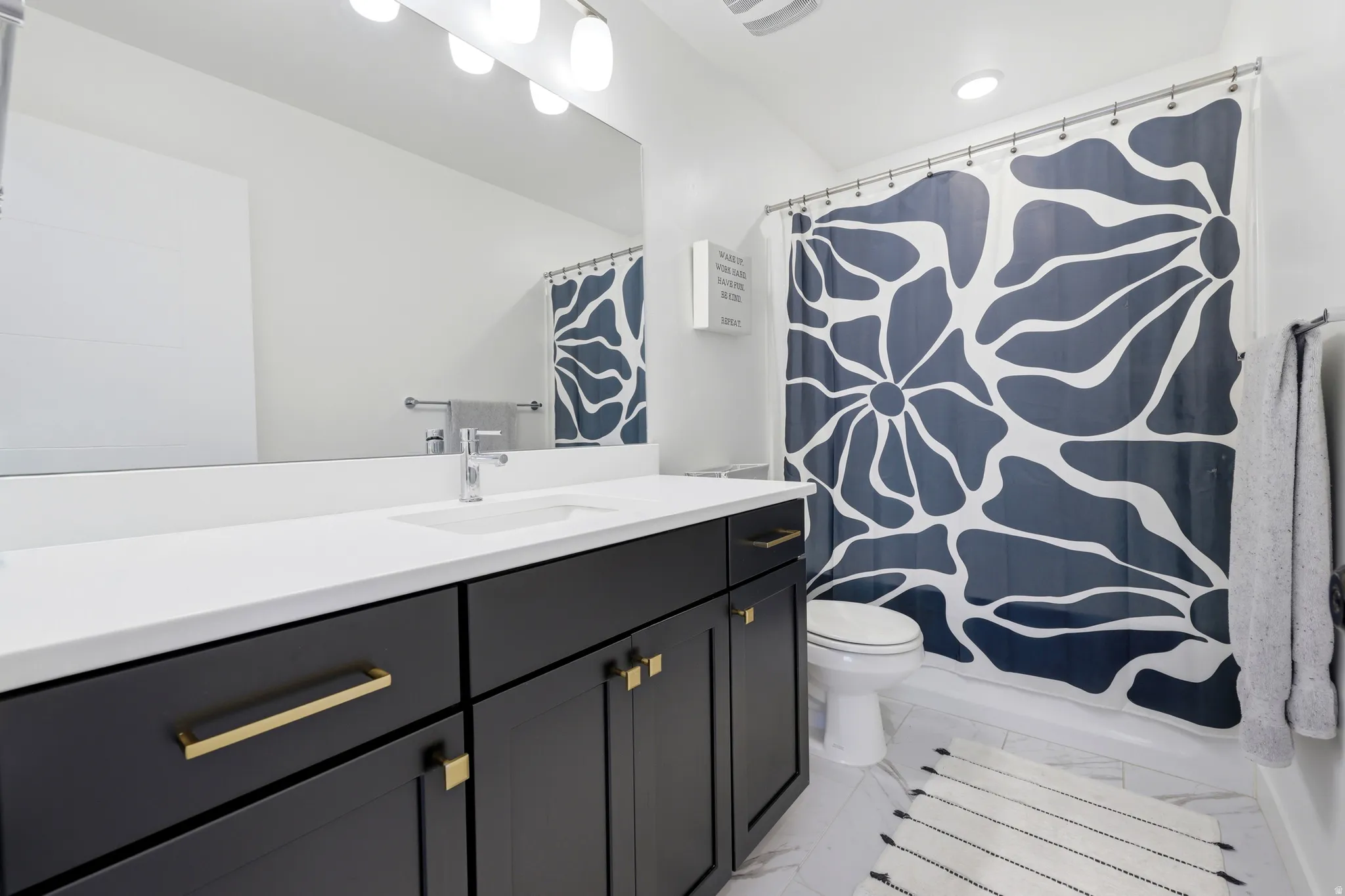 Bathroom featuring a dark wood-finish vanity with gold-tone hardware, a white countertop, and an undermount sink