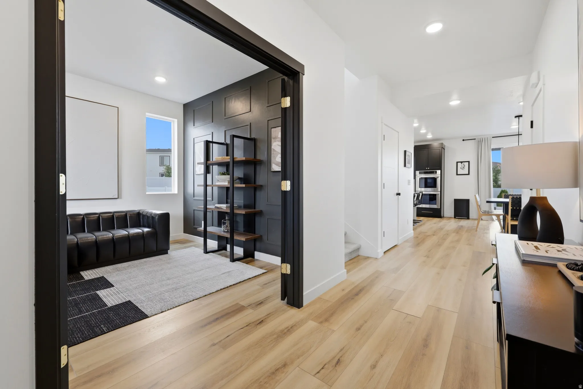 Open-concept living space featuring light wood-finish flooring, recessed lighting, and a defined entry to an additional room