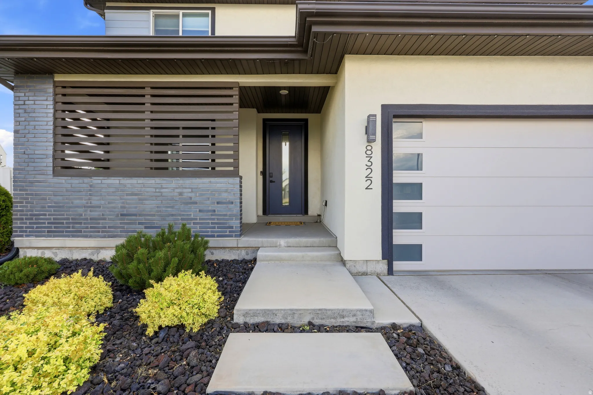Modern exterior featuring a dark gray brick facade, horizontal slat accent, and an integrated garage with frosted glass panels