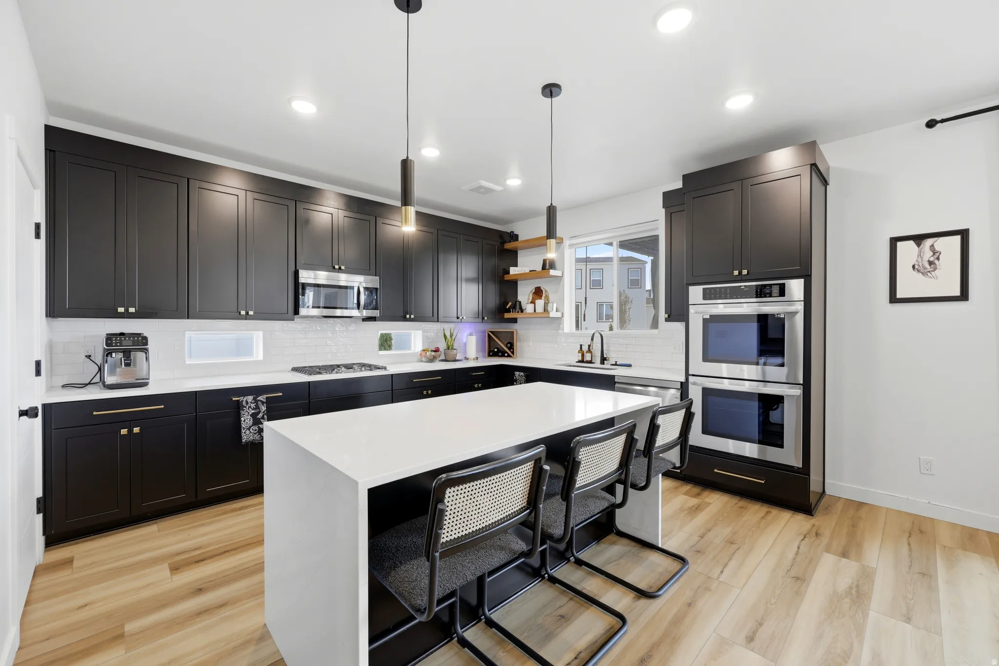 Contemporary kitchen featuring black cabinetry and light-finish flooring