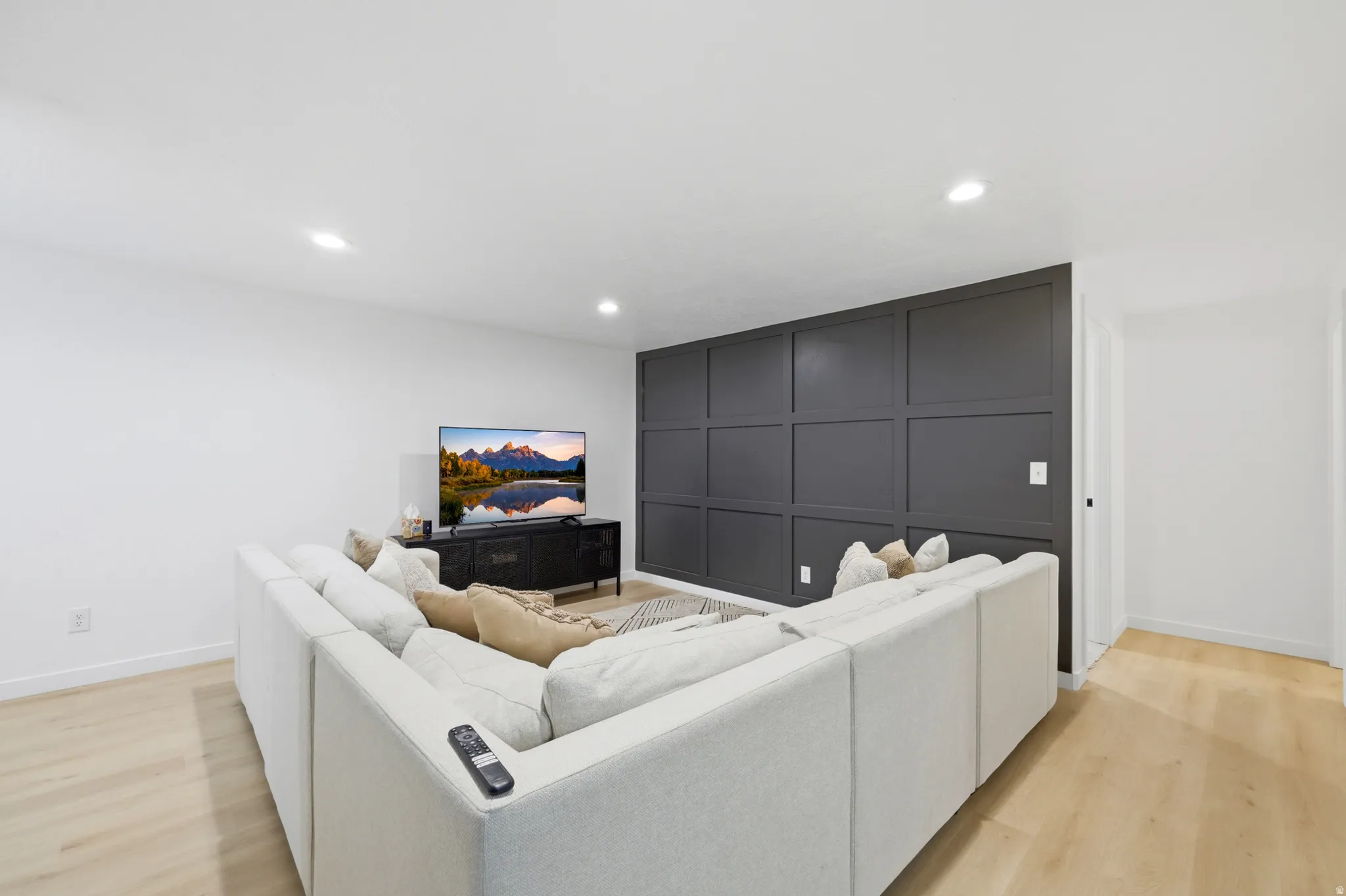 Accent wall with panel molding, light wood-finish flooring, recessed lighting, and white baseboards