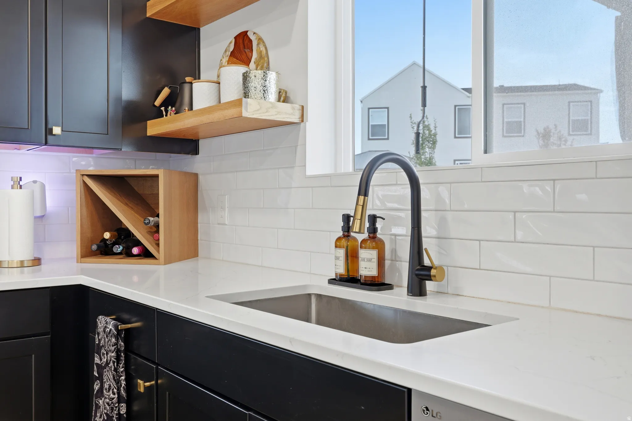 Contemporary kitchen sink with a black and gold gooseneck faucet, set within a light-toned countertop