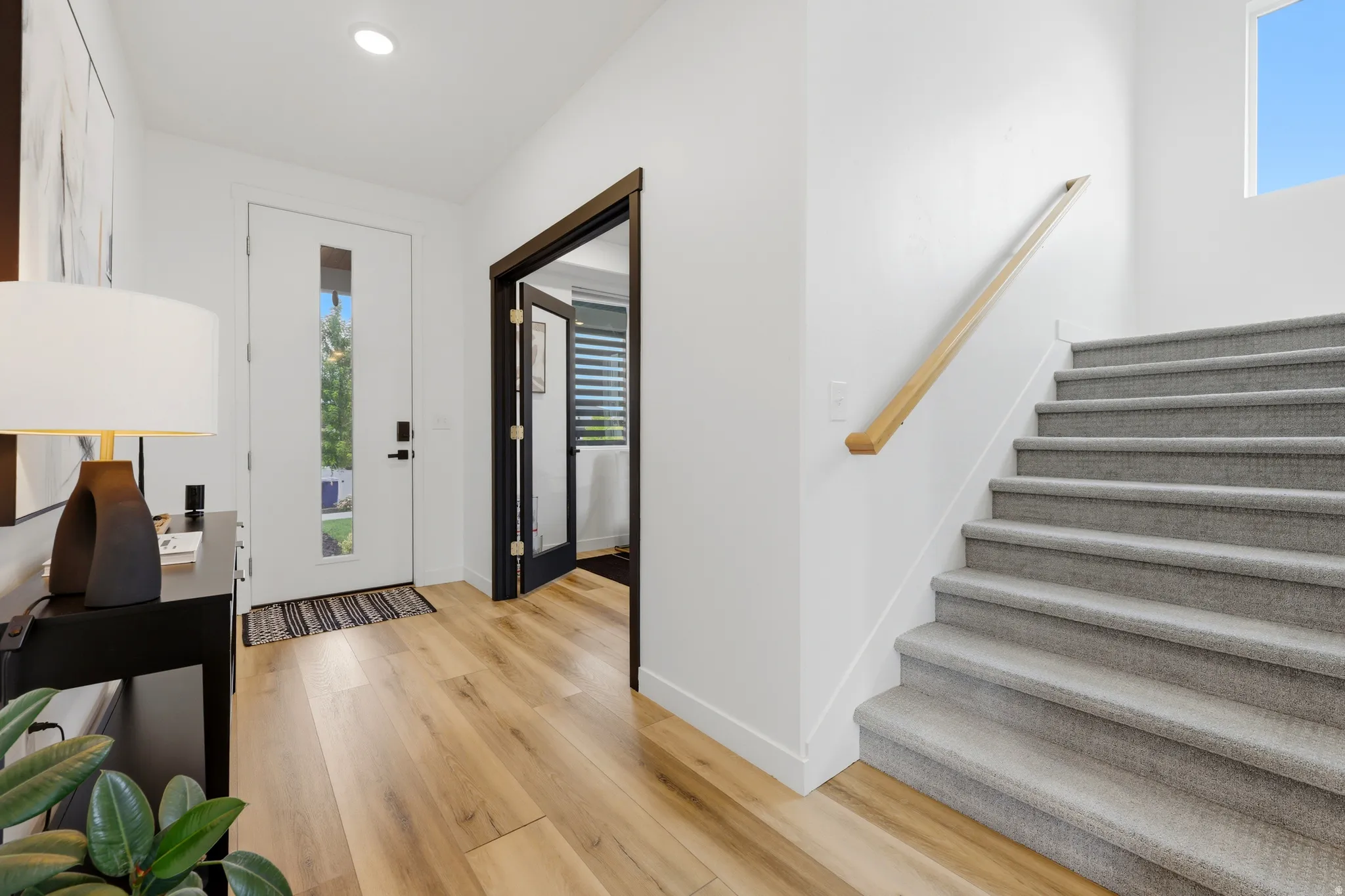 Entry foyer featuring wood-finish flooring and a contemporary white door with frosted glass paneling