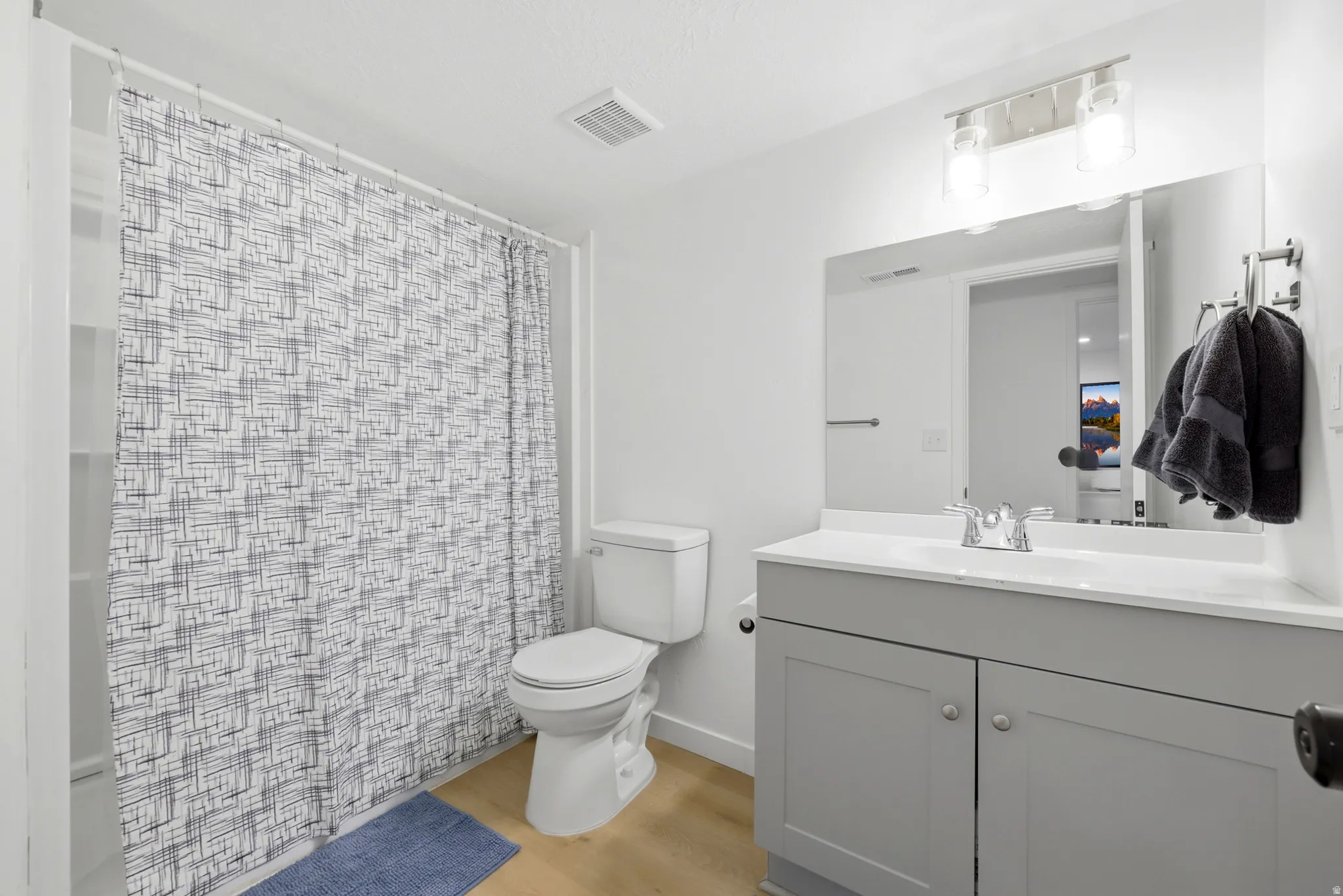 Bathroom featuring a shower-tub combination, a toilet, and a vanity with a white countertop