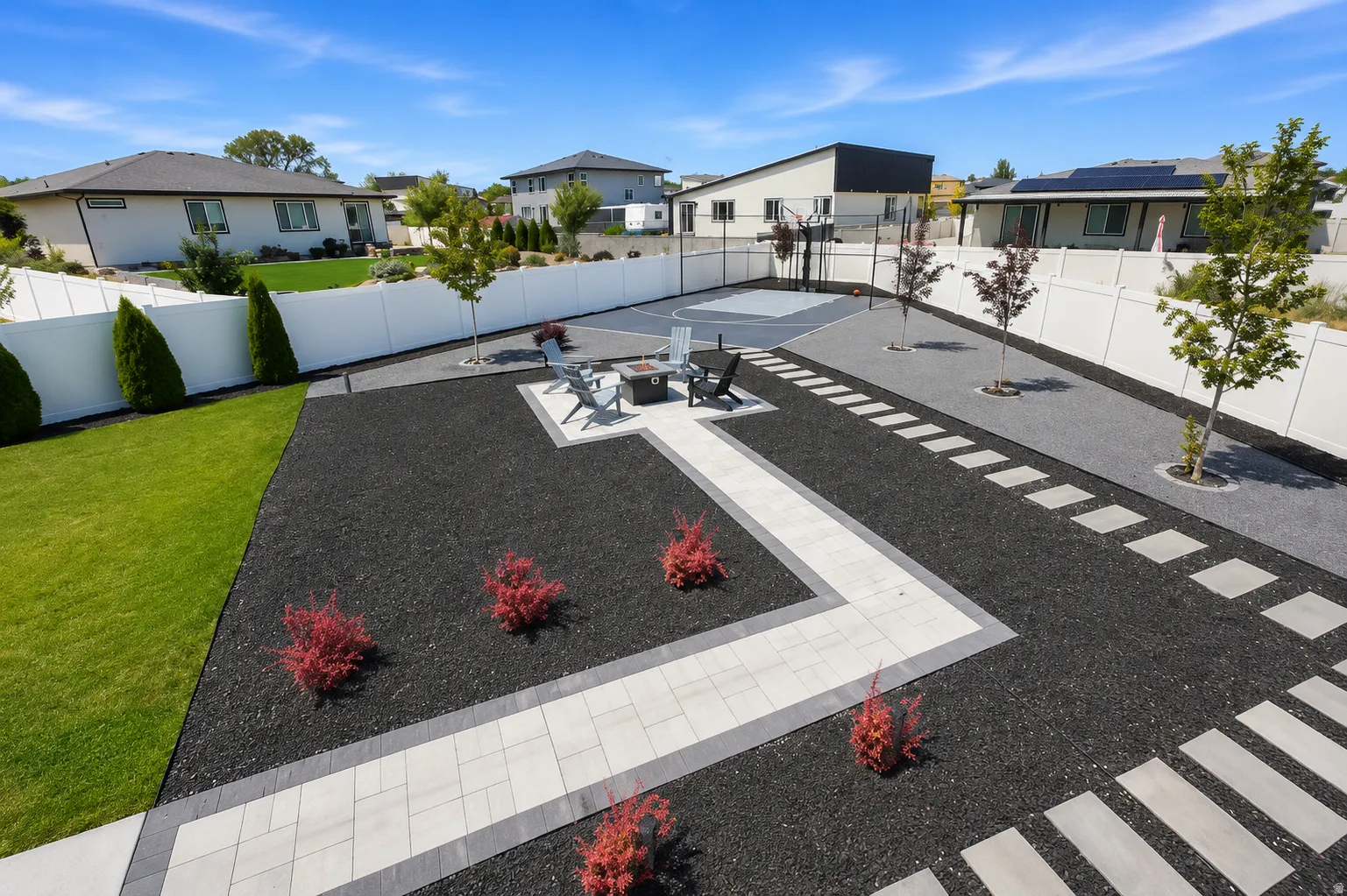 Expansive hardscaped yard featuring a paver patio with a fire pit, a dedicated sports court, and an artificial turf area