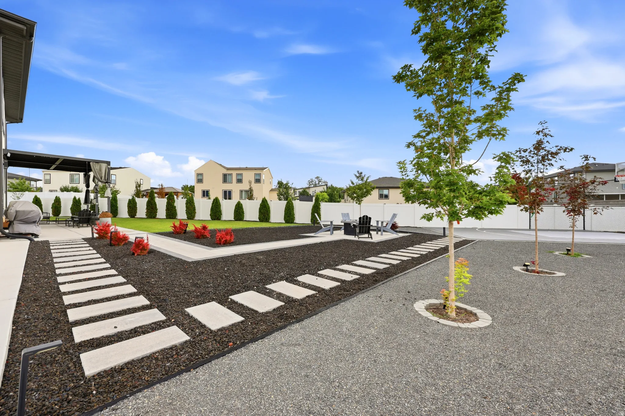 Spacious outdoor area featuring a covered patio, a manicured lawn, and decorative stepping stones