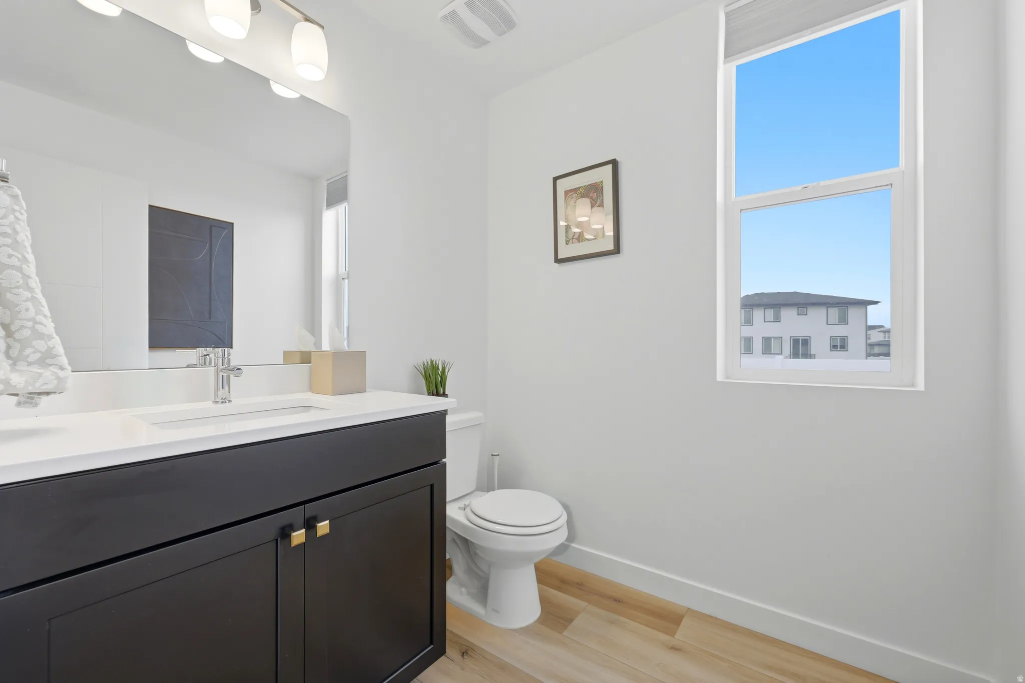 Modern bathroom featuring a dark wood-finish vanity with gold-tone hardware, a white countertop, and a rectangular sink