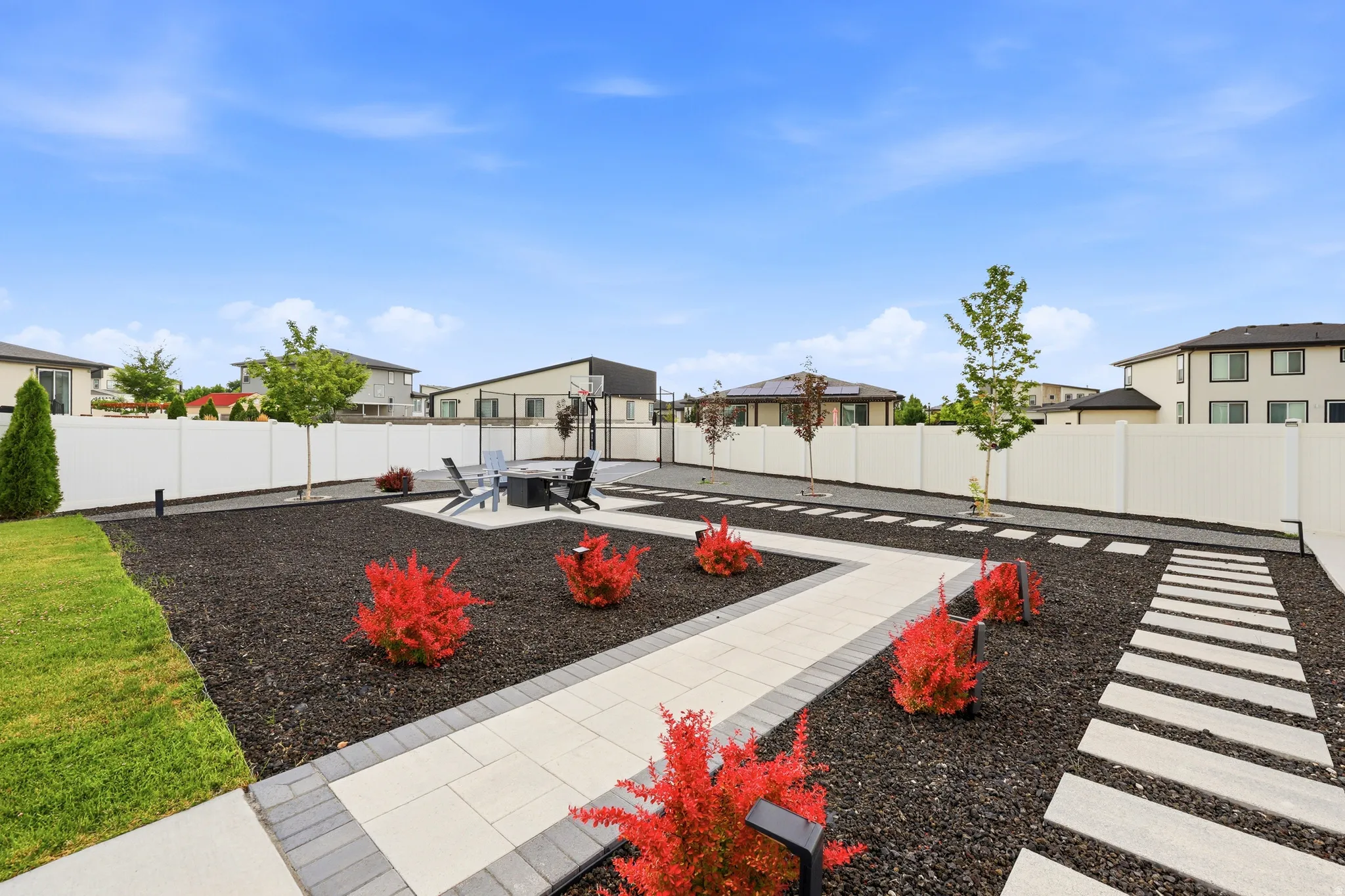 Landscaped backyard featuring paver pathways, decorative gravel beds, and a perimeter fence