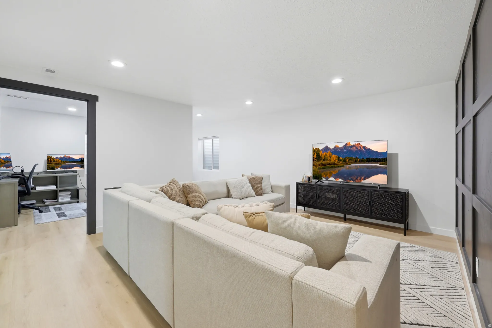 Light wood-finish flooring complements white walls and recessed lighting in this spacious area