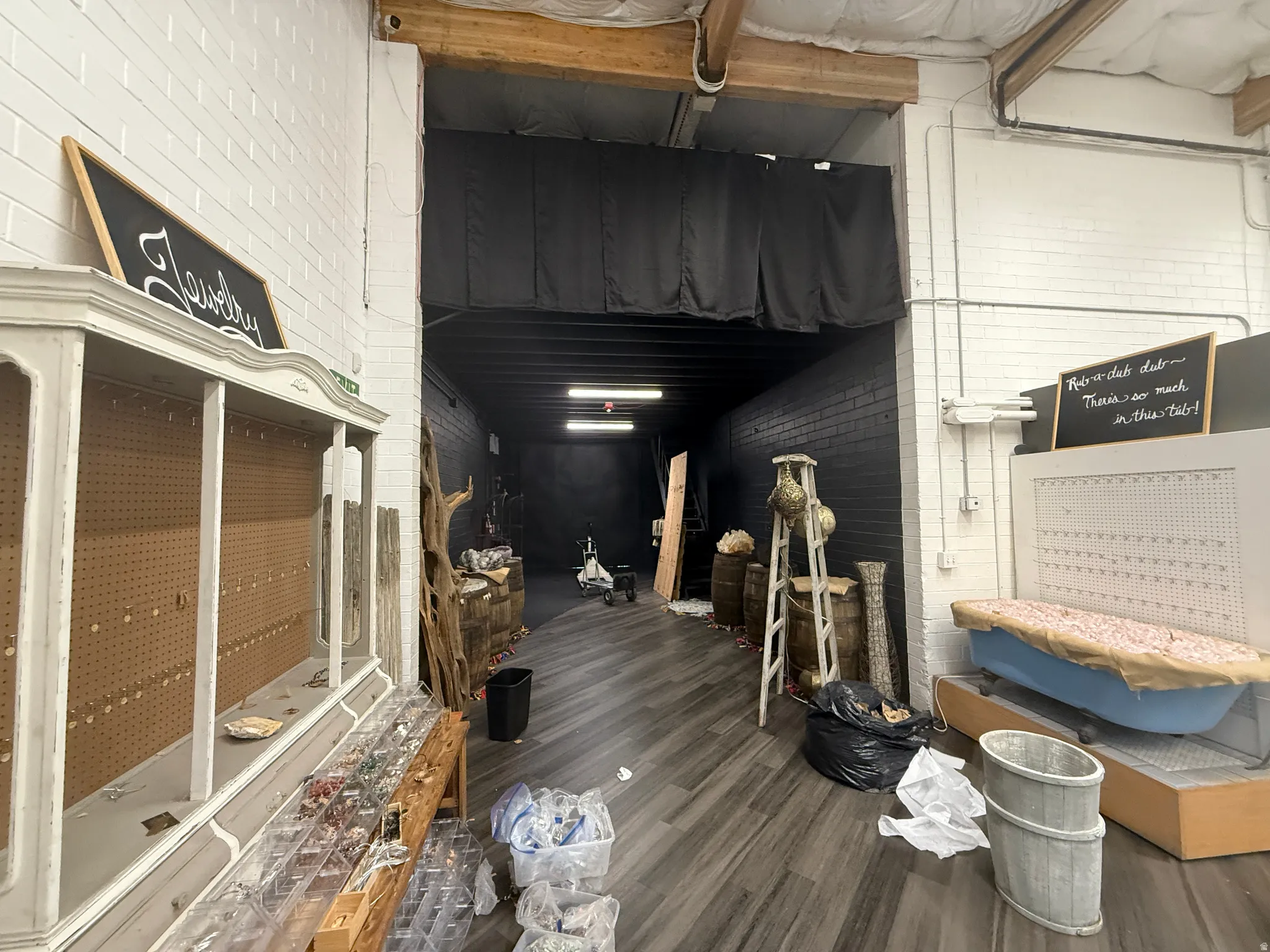 Commercial space featuring durable wood-finish flooring, white brick walls, and exposed ceiling beams