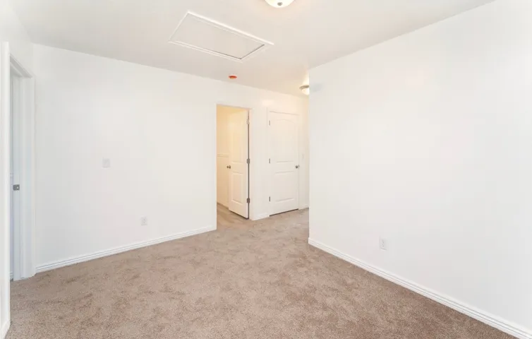 Spacious bedroom featuring neutral wall finishes, carpet flooring, and ample natural light from recessed ceiling fixtures