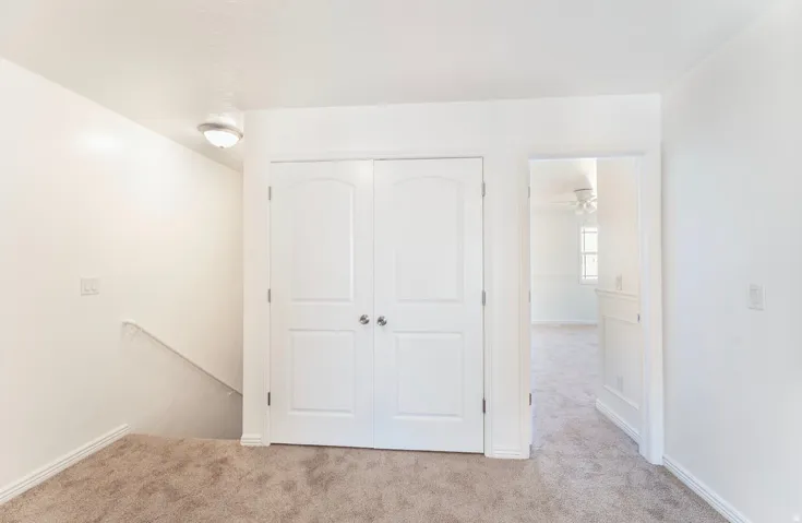 Spacious bedroom featuring neutral carpeting, dual closet doors with six-panel design, and abundant natural light from recessed ceiling fixtures