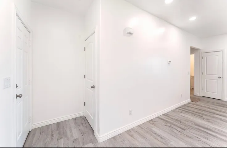 Entryway featuring wood-finish flooring, white baseboards, recessed ceiling lighting, and white paneled doors