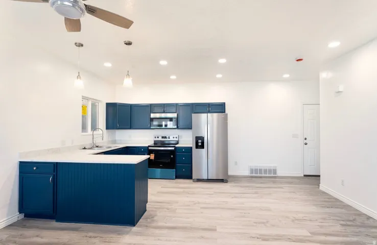Kitchen featuring a U-shaped island with beadboard paneling, white countertops, and blue cabinetry