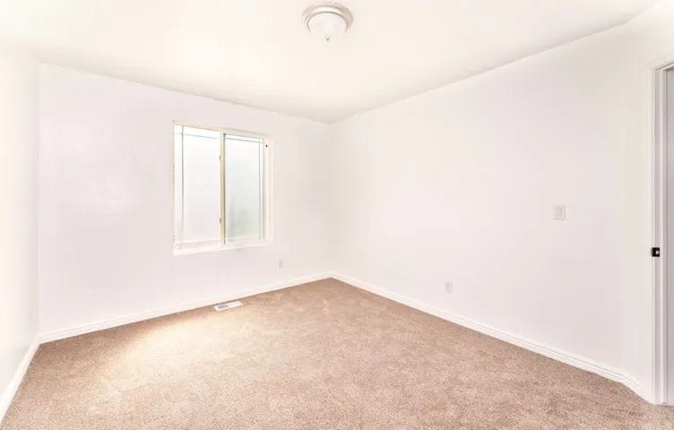 Carpeted room featuring a double-pane window with horizontal blinds, white baseboards, and a flush-mount ceiling light fixture