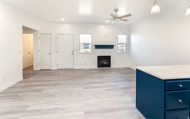 Spacious open-concept living area featuring wood-finish flooring, a gas fireplace with dark tile surround, and ample natural light from multiple windows