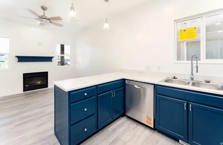 Contemporary kitchen featuring custom navy cabinetry with brushed nickel hardware, white quartz countertops, and stainless steel appliances including a built-in dishwasher and gas cooktop